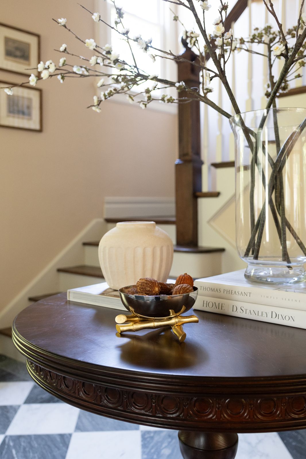 Round mahogany entry table with blossoms, brass bowl and staircase