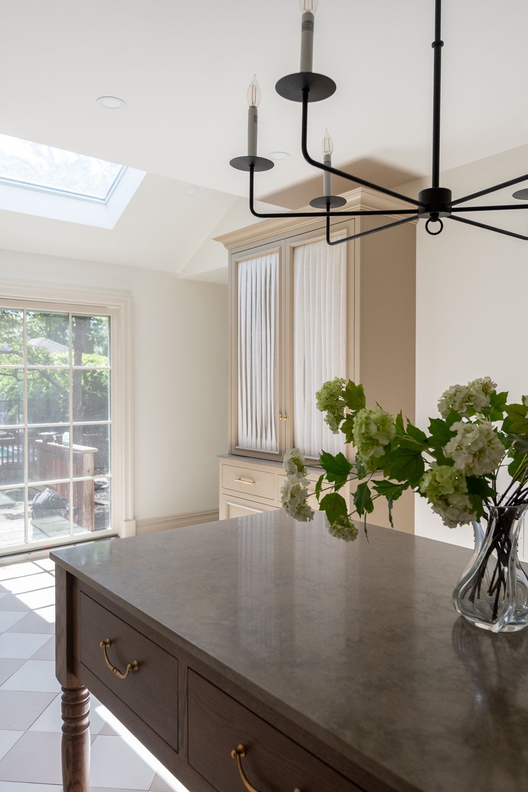 Kitchen with curtain-front cabinet, skylight and iron chandelier